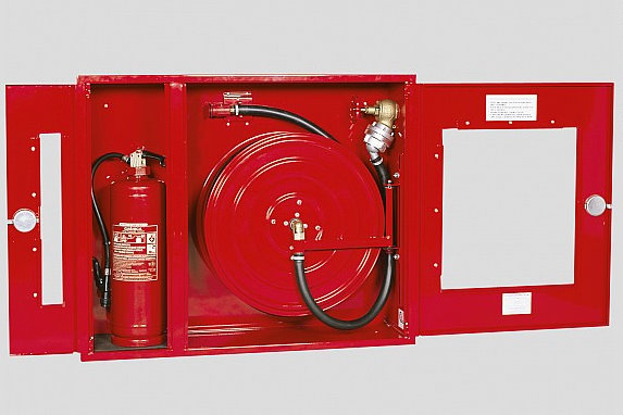 Czerwona szafka hydrantowa z otwartymi drzwiami, zawierająca zwinięty wąż strażacki i gaśnicę proszkową.